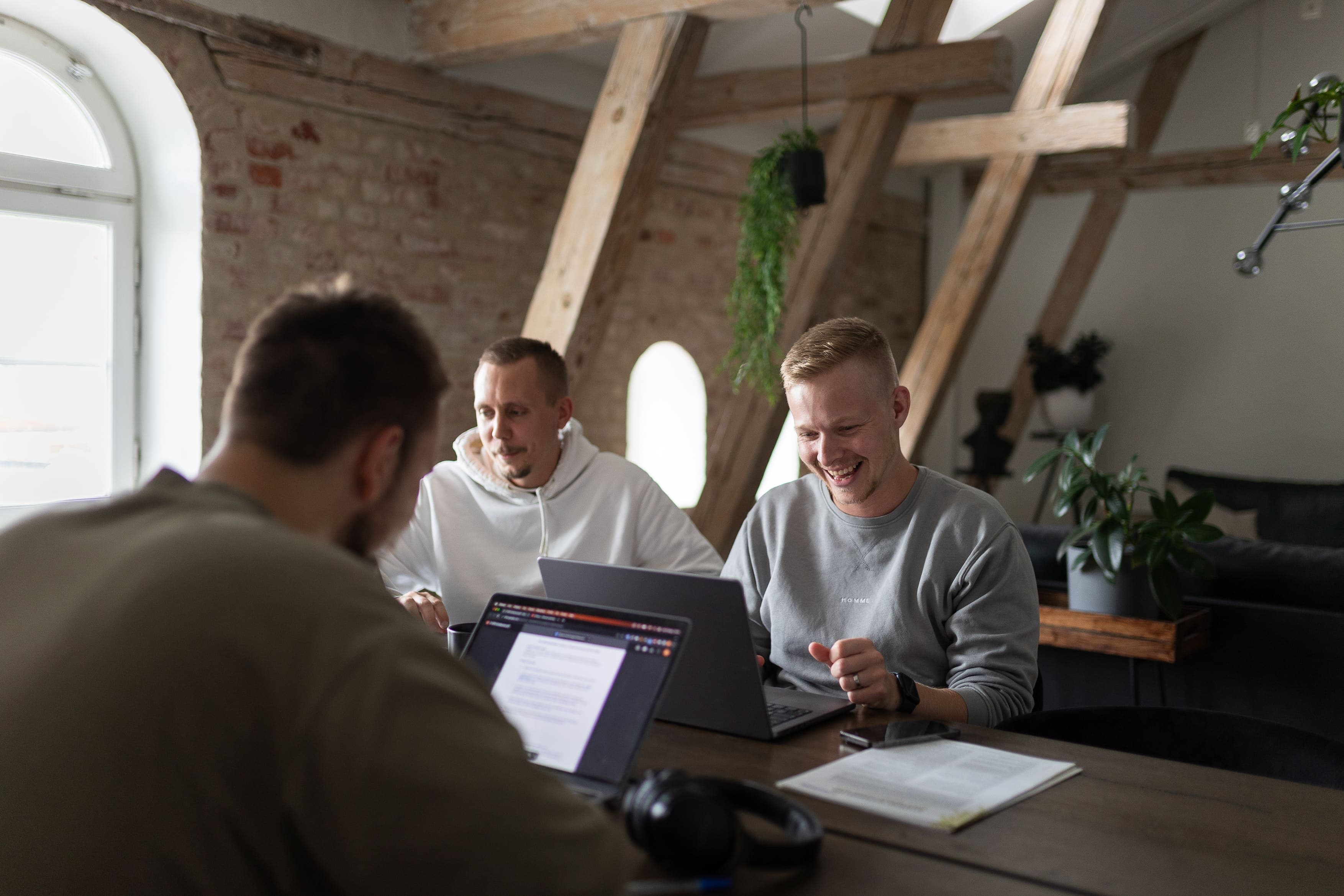 Joel, Marcus and David are sitting at the office working and laughing